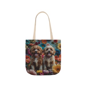 Könnte beinhalten: Eine Tragetasche mit einem farbenfrohen Blumendesign und zwei Welpen. Die Tasche hat einen cremefarbenen Griff und ein farbenfrohes Design aus Blumen in Rot-, Gelb- und Blautönen. Die Welpen haben braunes und weißes Fell.