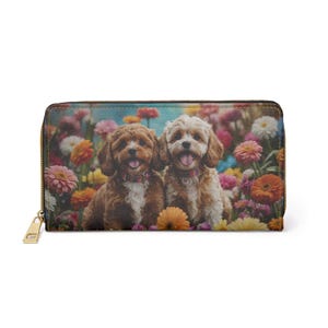 May include: A zippered wallet featuring a colorful floral design with two adorable puppies. The puppies are brown and cream-colored, with their tongues out, set against a backdrop of vibrant flowers. The wallet has a gold-colored zipper.