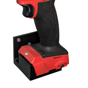 May include: A red and black Milwaukee FUEL drill with a black wall mount. The drill has a black chuck and a red and black battery.