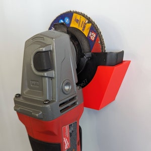 May include: A red and gray angle grinder with a black and blue grinding disc attached to a red wall mount. The grinding disc has the text "50 Grit 3,000 RPM 80"