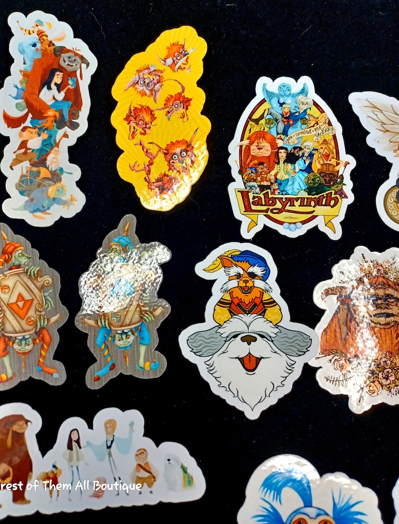 May include: A collection of colorful stickers featuring characters and scenes from the movie Labyrinth. The stickers include images of goblins, the Fireys, and other fantasy creatures. The stickers are on a black background.