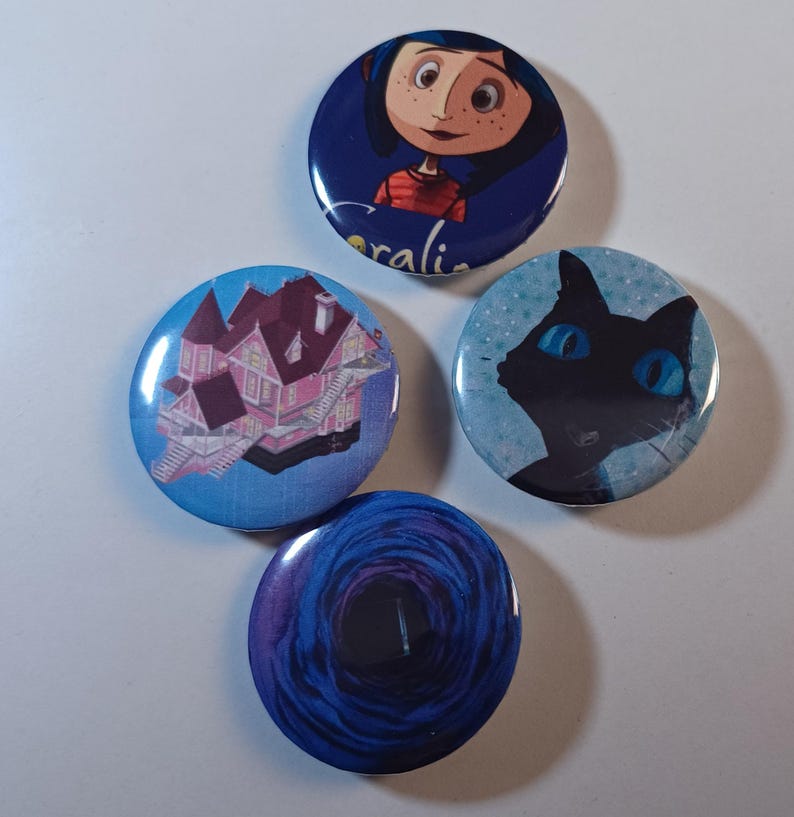 May include: Four round buttons with images from the animated film "Coraline." One button features a girl with the name "Coraline" below. Other buttons show a pink house, a black cat with blue eyes, and a blue tunnel.