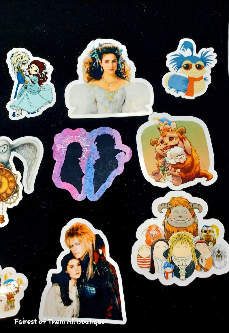 May include: A collection of colorful stickers featuring characters from the movie Labyrinth. The stickers include images of Jareth the Goblin King, Sarah, Hoggle, and other iconic characters. The stickers are on a black background.