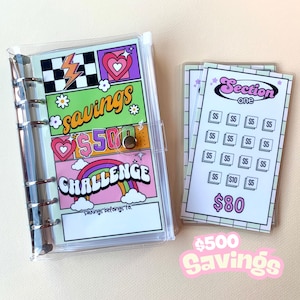 May include: A clear plastic binder with a colorful page that says "savings $500 challenge". The page has a rainbow, hearts, and lightning bolts. There are also several clear plastic pages with a grid pattern and the text "Section one" and "$80".