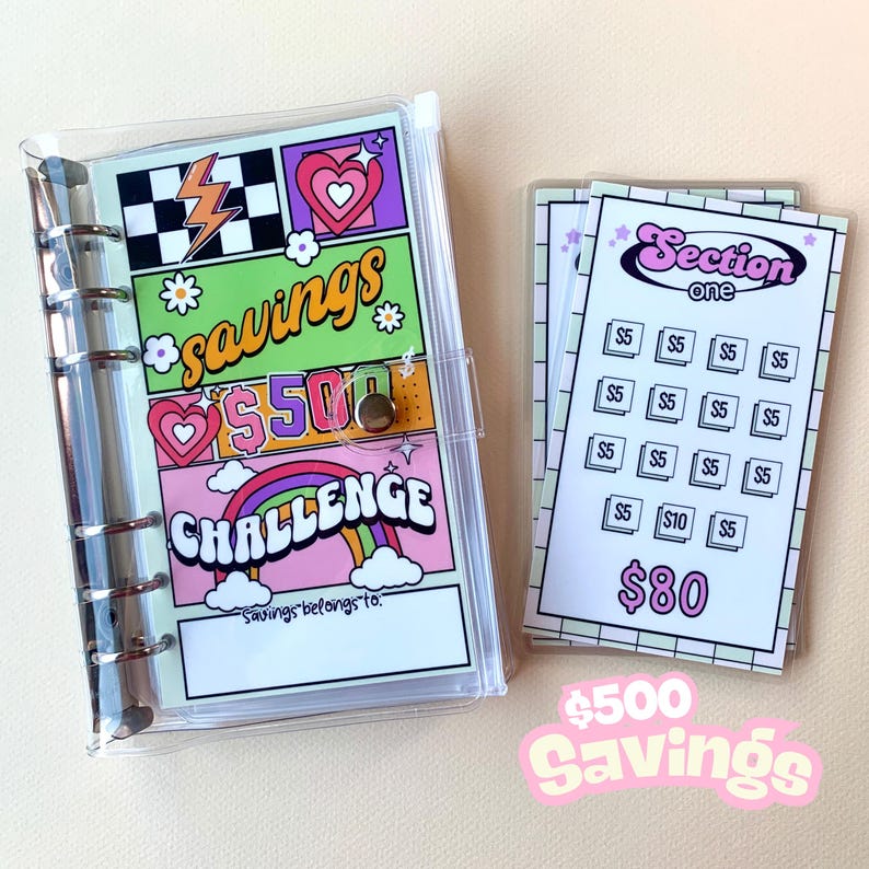 May include: A clear plastic binder with a colorful page that says "savings $500 challenge". The page has a rainbow, hearts, and lightning bolts. There are also several clear plastic pages with a grid pattern and the text "Section one" and "$80".