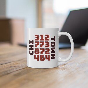 May include: White ceramic mug with a black and red design featuring the words "CHI TOWN" and the numbers "312 773 872 464".