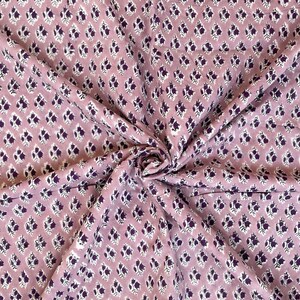 Puede incluir: Primer plano de una tela con un patr&oacute;n repetido de peque&ntilde;as formas florales de color p&uacute;rpura oscuro sobre un fondo malva claro. La tela est&aacute; reunida y doblada, mostrando la textura y la ca&iacute;da del material.