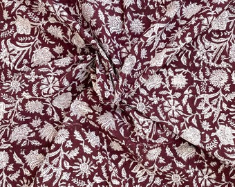 May include: A close-up of a burgundy fabric with a white floral pattern. The fabric is folded in the center, creating a swirl effect.