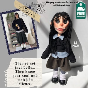 Könnte beinhalten: Handgefertigte Puppe mit schwarzen Haaren, Knopfaugen und genähtem Mund. Die Puppe trägt eine schwarze Jacke, ein blaues Hemd und einen braunen Rock. Sie ist 30.48 cm groß. Text: "They're not just dolls... They know your soul and watch in silence."