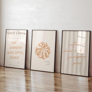 May include: Three framed art prints with black frames. The first print reads "Guest Check" and "one pumpkin spice latte, please." The second print has a drawing of a pastry and the words "happy fall." The third print says "autumn skies and pumpkin pies."
