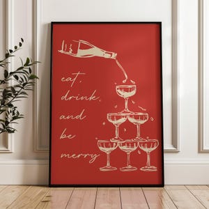 K&ouml;nnte beinhalten: Ein roter Poster mit einer wei&szlig;en Umrandung einer Champagnerflasche, die in einen Stapel Champagnergl&auml;ser gegossen wird. Der Text "eat, drink, and be merry" ist in wei&szlig; auf der linken Seite des Posters geschrieben.