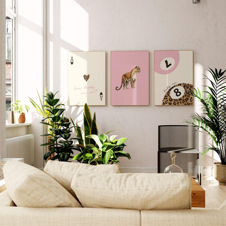 May include: Three pink and cream framed prints with a leopard print design. The left print features a playing card with a heart and the text "how lucky are we?" The middle print features a leopard. The right print features a leopard print with a large number 8 and the text "lucky me".