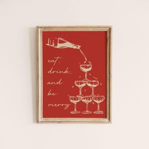 K&ouml;nnte beinhalten: Ein roter Hintergrund mit einer wei&szlig;en Umrandung einer Champagnerflasche, die in einen Stapel Champagnergl&auml;ser gegossen wird. Der Text "eat, drink, and be merry" ist in Wei&szlig; geschrieben.