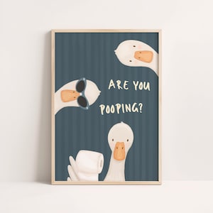 Puede incluir: Impresión enmarcada con tres gansos de dibujos animados sobre un fondo azul a rayas. Un ganso lleva gafas de sol, otro sostiene papel higiénico y se muestra el texto "ARE YOU POOPING?"