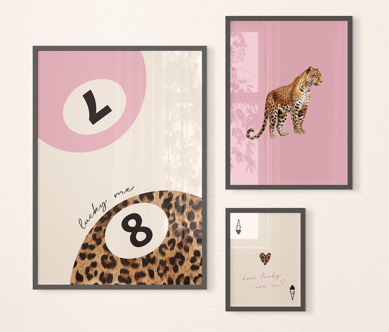 May include: Three framed prints with a pink background. The first print features a pink circle with the number "7" inside, the second print features a leopard print circle with the number "8" inside and the text "lucky me" above it, and the third print features a leopard print with the text "how lucky are we?" and an ace of spades card.