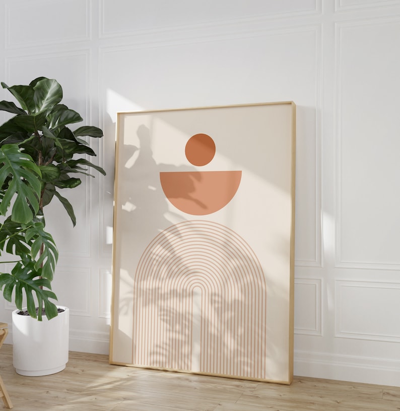 May include: A framed print with a minimalist geometric design featuring a peach-colored circle, half-circle, and a series of arches in a light brown color.
