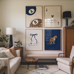Op de afbeelding: Vier ingelijste prints op een witte muur. De print linksboven heeft een blauwe cirkel met de letter L en het nummer 8 in een cirkel met luipaardprint. De print rechtsboven heeft een speelkaart met de Aas van Schoppen en een hart met de tekst "how lucky are we?" De print linksonder heeft een blauw lint met de tekst "With free hand dreaming big." De print rechtsonder heeft een luipaard op een blauwe achtergrond.