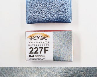 May include: A watercolour paint pan with the brand name "Semse Art Paints Watercolour" and the number "227F" printed on the label. The label also says "Kalseon Chalcedony". The paint pan is a light blue colour with a shimmery finish.