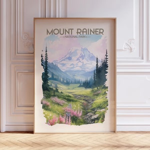 May include: A vintage-style poster featuring a watercolor illustration of Mount Rainier National Park. The poster has a light blue background with a mountain range in the distance and a lush green valley in the foreground. The text "Mount Rainier - National Park -" is printed in brown at the top of the poster.