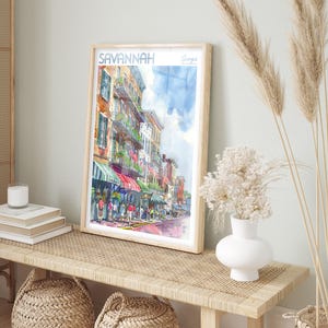 May include: A watercolor painting of a street scene in Savannah, Georgia. The painting depicts a street lined with colorful buildings, shops, and people walking by. The title "SAVANNAH Georgia" is written in the top left corner of the painting.