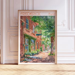 May include: A watercolor painting of a brick building with a green door and windows. The building is located on a street with trees and other buildings in the background. The painting is titled "FREDERICK Maryland".