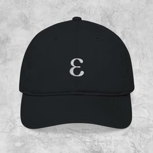 May include: A black baseball cap featuring a silver embroidered Greek letter epsilon. The cap has a curved brim and a structured crown. The design is simple and minimalist, suitable for everyday wear.