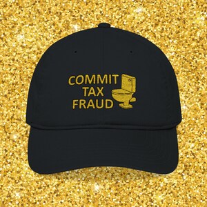 May include: Black baseball cap with the words "COMMIT TAX FRAUD" embroidered in gold, along with a gold toilet graphic. The cap has a curved brim and a fabric strap closure.
