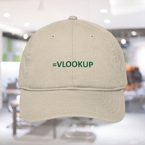 May include: A beige baseball cap with the text "=VLOOKUP" embroidered in green across the front. The cap has a curved brim and a classic six-panel design, suitable for casual wear.