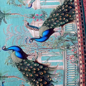 May include: A fabric textile featuring a repeating pattern of vibrant blue and green peacocks with long, detailed tail feathers. The scene includes architectural stone columns, lush palm trees, and floral elements set against a bright turquoise background.