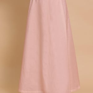 May include: A solid light pink ankle-length skirt featuring a high-waisted design with an elastic waistband and a matching drawstring tie at the center. The skirt has a simple, flared silhouette that falls straight down from the waist to the hem.