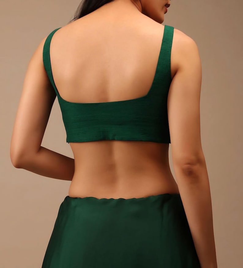 Puede incluir: Un top corto sin mangas de color verde oscuro con un amplio escote cuadrado y una silueta ajustada. La prenda est&aacute; confeccionada en una tela de color s&oacute;lido con una sutil textura horizontal, mostrando un dise&ntilde;o limpio con tirantes anchos.