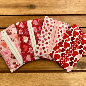 May include: Four handmade tissue holders with a Valentine's Day theme. Each holder features a different red and pink heart pattern.