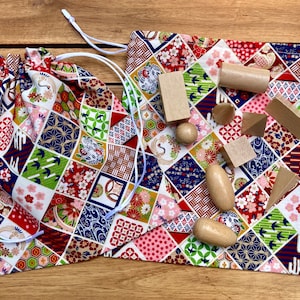 May include: Two drawstring bags with a colorful Japanese-inspired patchwork design. The bags are filled with wooden blocks and other shapes.