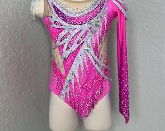 May include: A pink and silver leotard with a long sleeve on one side. The leotard is decorated with rhinestones and sequins.