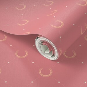 May include: A roll of pink wallpaper with a repeating pattern of gold horseshoes and white dots.