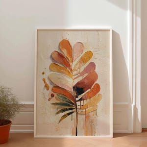 Könnte beinhalten: Abstrakter Kunstdruck in einem weißen Rahmen, der ein stilisiertes Blatt darstellt. Das Kunstwerk verwendet warme Farben wie Orange, Gelb und Rosa auf einem strukturierten Hintergrund. Das Blattdesign hat ein unverwechselbares, geschichtetes Aussehen.