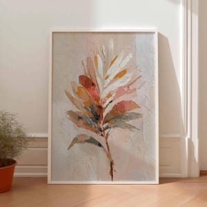 Könnte beinhalten: Gerahmtes abstraktes Gemälde einer Pflanze mit großen, strukturierten Blättern. Die Blätter sind in Weiß-, Orange-, Rosa- und Grüntönen auf einem neutralen Hintergrund gemalt. Das Kunstwerk wird in einem weißen Rahmen präsentiert.