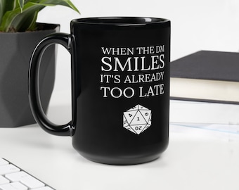 May include: Black ceramic mug with a white design that reads "When the DM smiles it's already too late" and a white 20-sided die graphic.