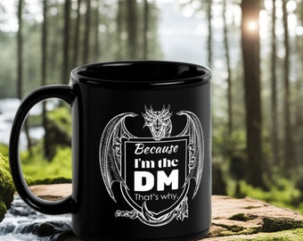 May include: Black ceramic coffee mug with a white dragon design and the text "Because I'm the DM That's why."