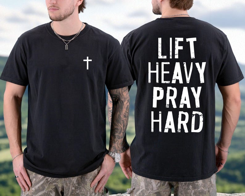 May include: Black t-shirt with a white cross on the front and the words "LIFT HEAVY PRAY HARD" on the back. The shirt is a crew neck and has short sleeves. The shirt is made of a soft material.