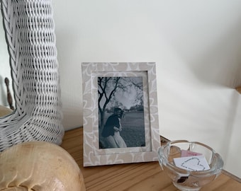 Marco de fotos y tapete envueltos en papel con motivos florales neutros