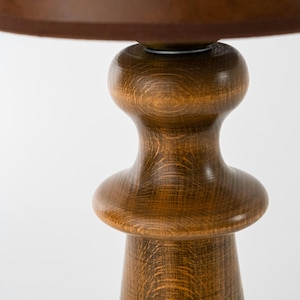May include: A wooden table base with a brown finish. The base has a rounded, turned design with a smooth, polished surface.