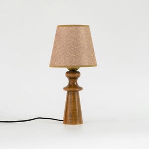 May include: A wooden table lamp with a brown fabric lampshade. The lamp has a simple, modern design and is perfect for adding a touch of warmth to any room.