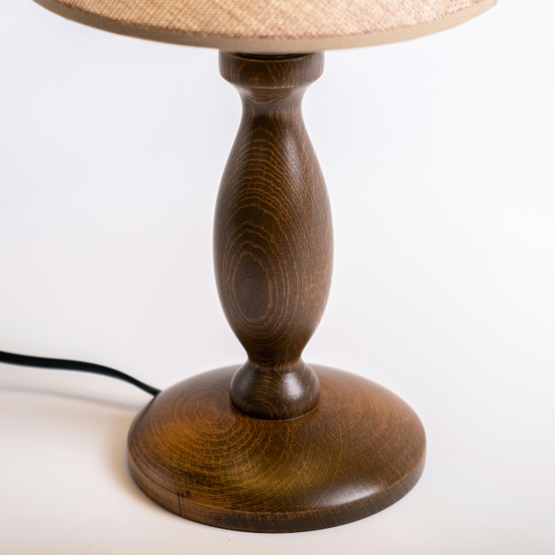 May include: A wooden table lamp with a brown base and a beige lampshade.