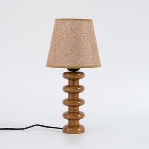 May include: A wooden table lamp with a brown fabric shade. The lamp base is made of stacked wooden circles.