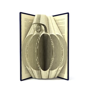 May include: A book with pages folded into the shape of a pumpkin. The book is open and the pages are folded to create a three-dimensional pumpkin shape. The book is closed on the left and right sides, and the spine is visible.