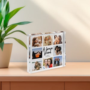 May include: A clear acrylic photo block featuring a collage of nine photos. The block has the words "A forever friend" and the names "Olivia and Emma" in black script. The photos show various people and scenes.