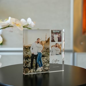 May include: A clear acrylic photo block featuring three images of a couple, with the words "Endless love" and names printed on the side. The main image shows the couple embracing on a rocky beach. The block sits on a black surface.