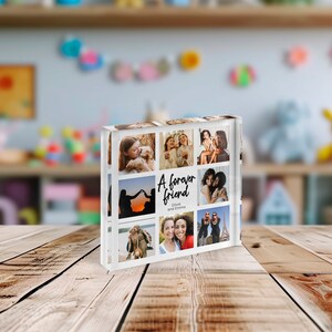 May include: A clear acrylic photo block featuring nine images of friends. The block has the text "A forever friend" with the names Olivia and Emma. The photos are of people, and the block is on a wooden surface.
