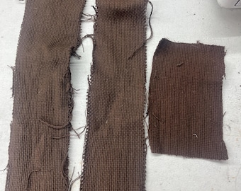 May include: Two long strips of brown fabric with frayed edges and a smaller square piece of the same fabric.